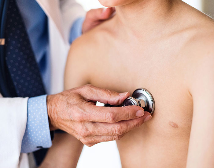 "Doctor examines child's chest with stethoscope, medical checkup attention."