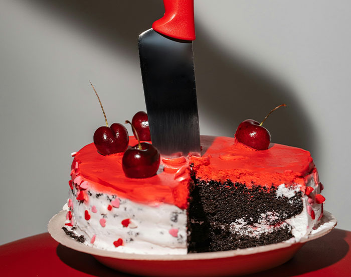 Knife in a cake with red icing and cherries, possibly indicating something unhinged for attention.