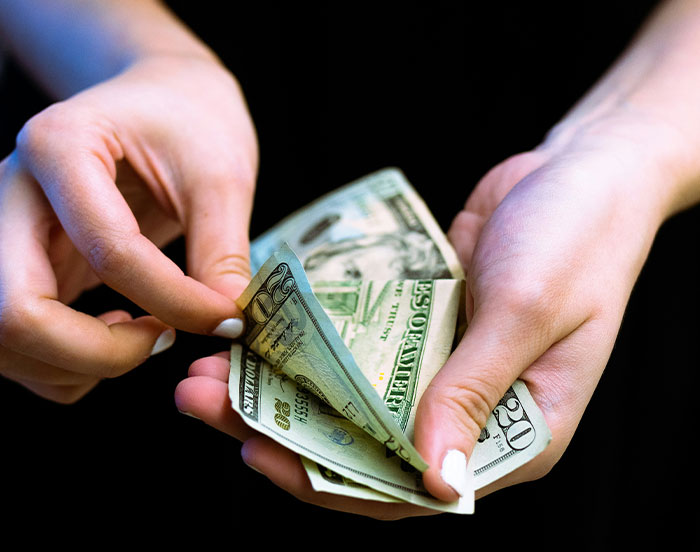Hands holding and counting dollar bills, related to unhinged actions for attention.
