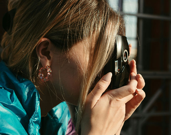 Person holding a camera up to their face, seemingly engaged in capturing a moment.