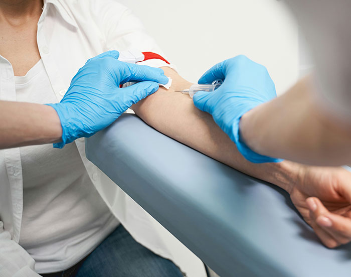 Individual receiving a blood test, medical professional using a needle with gloves, seeking attention in unusual ways.