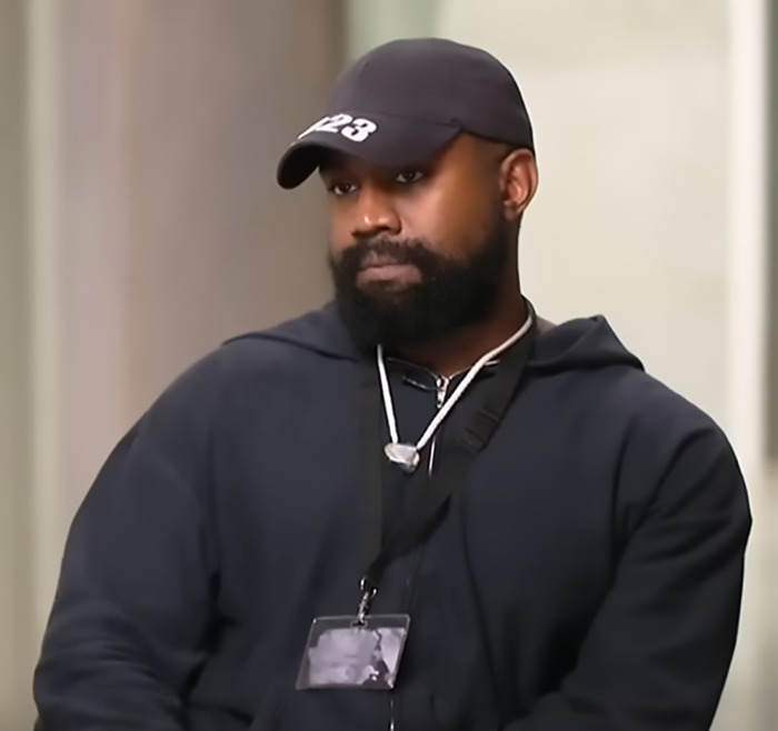 Man in a black cap and hoodie, seated indoors, reflecting Kanye West X-Rated AI meme theme. Man in a black cap and hoodie, seated indoors, reflecting Kanye West X-Rated AI meme theme.