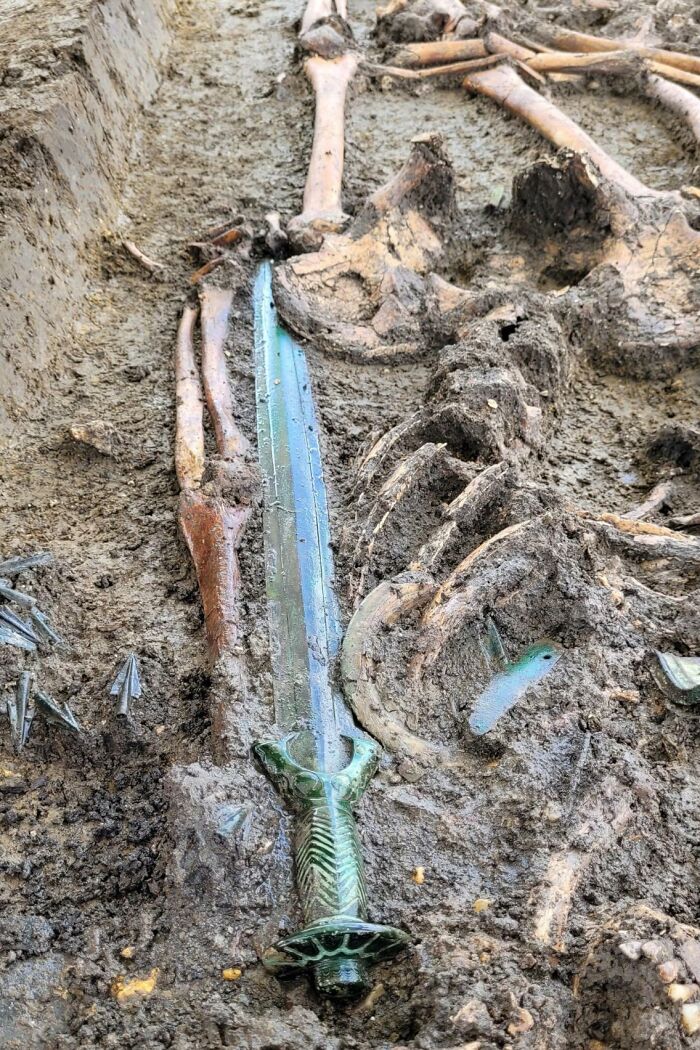 Ancient artefact: sword and skeleton unearthed in the mud, remarkably preserved.