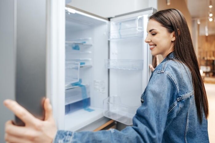 Person smiling while opening an empty refrigerator, demonstrating a life hack idea.