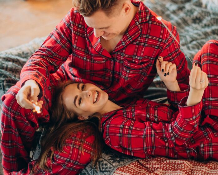 Couple in matching red plaid pajamas enjoying a cozy moment together as a simple Valentine's gift idea.
