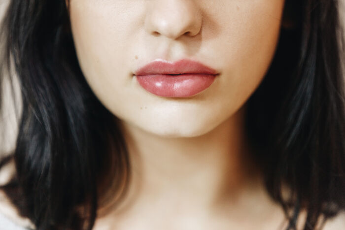 Close-up of a woman with glossy lips reflecting recent fashion trends people hate.
