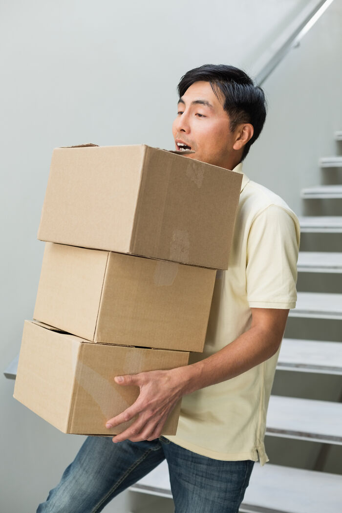 Man carrying stacked boxes up stairs, illustrating cool "Today I Learned" fact in action.