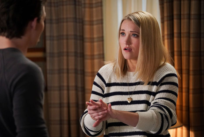Emily Osment from Young Sheldon cast in a striped sweater, gesturing emotionally indoors.