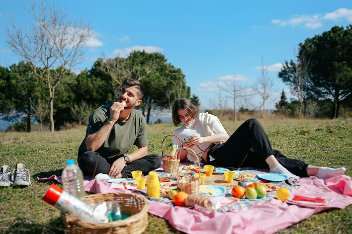 A couple enjoying a picnic with a basket, fruits, and snacks, representing simple Valentine's gift ideas.