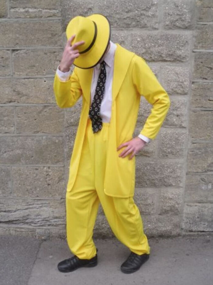 Person in a bright yellow suit and hat, posing awkwardly like a job interview gone wrong.