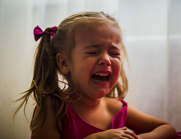 Young girl in a pink dress crying, illustrating child inclusion issues at a spa event.