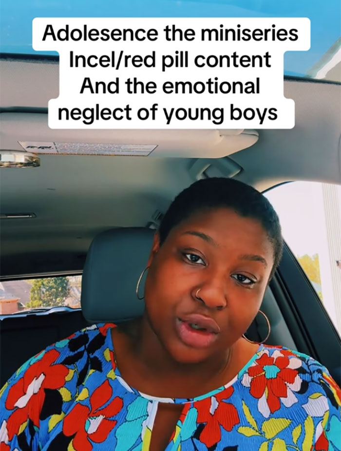 Woman discusses red pill culture and emotional neglect of boys, wearing a colorful top in a car. Woman discusses red pill culture and emotional neglect of boys, wearing a colorful top in a car.