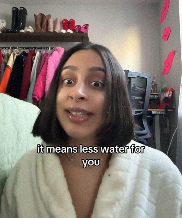 Woman discusses AI's environmental impact in a cozy room setting with clothing and shoes in the background.