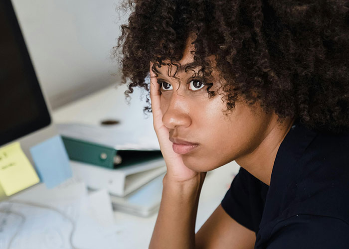 Young woman contemplating beside a desk with folders, reflecting thoughts on property investment and relationships.