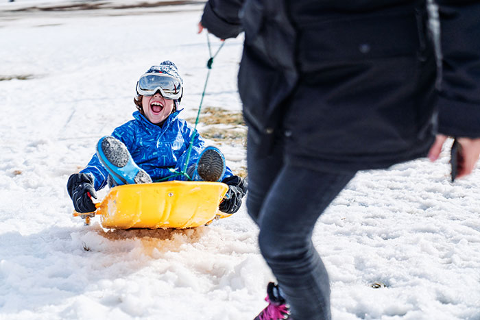 Child sledding in the snow, enjoying winter fun, highlighting reasons to move to a blue state.