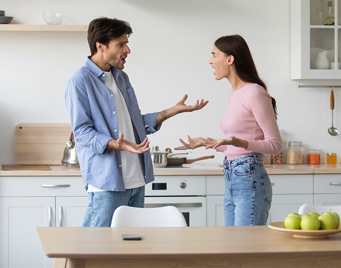 Man and woman arguing in kitchen about cooking and decorating, surrounded by kitchenware and produce. Man and woman arguing in kitchen about cooking and decorating, surrounded by kitchenware and produce.