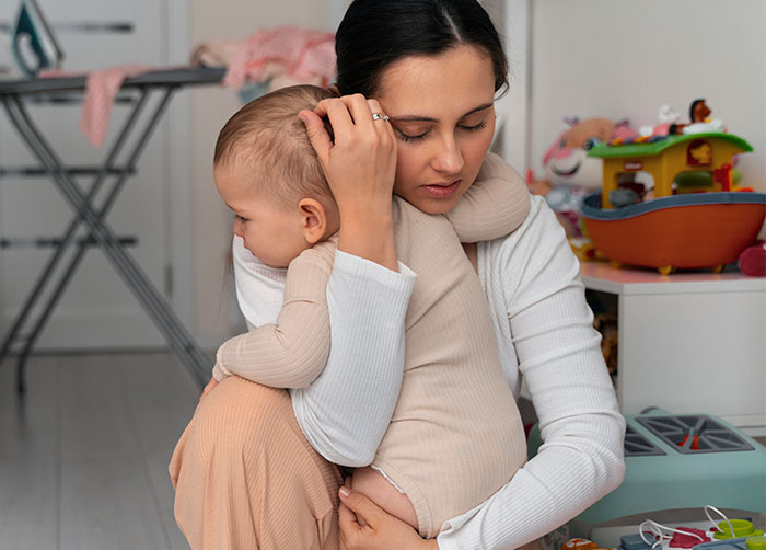 A woman holding a toddler in a playroom, illustrating an unplanned D&D night disruption. A woman holding a toddler in a playroom, illustrating an unplanned D&D night disruption.