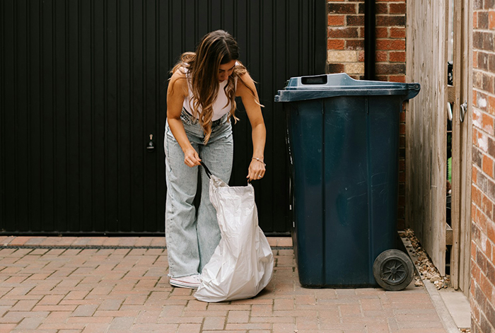 Woman retrieves items from trash can, alleged stealing incident unfolds.