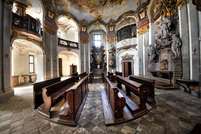 Abandoned chapel interior with ornate architecture and weathered pews, showcasing beauty over time.