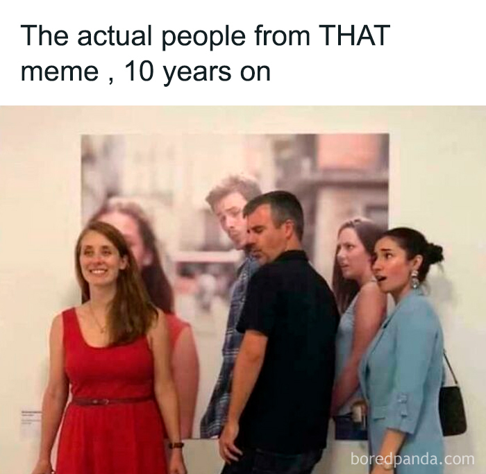 People pose humorously in front of a famous meme poster, showcasing where laughter lives in a fun setting.