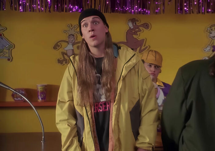 Fan having a funny interaction with a celebrity at a colorful counter, with cartoon characters on the yellow wall.