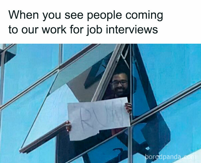 Man holding 'RUN' sign through office window, part of funny memes collection.