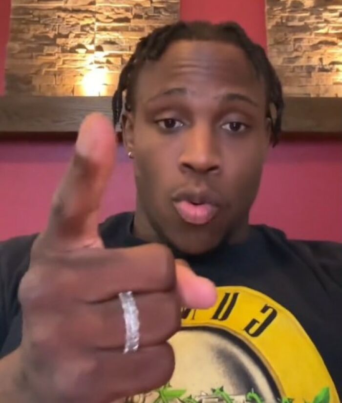 Man discussing 'big boys don't cry' parenting, wearing a black graphic tee, pointing at the camera. Man discussing 'big boys don't cry' parenting, wearing a black graphic tee, pointing at the camera.