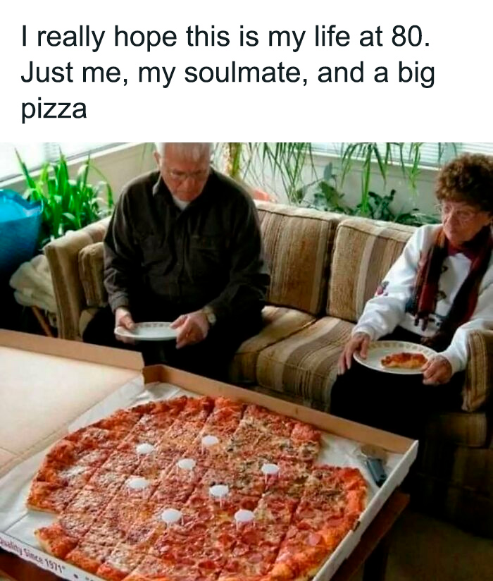 Elderly couple enjoying a massive pizza on a couch, capturing chaotic food humor.