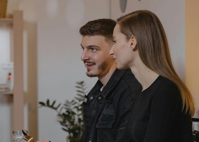 Two people smiling and talking indoors, illustrating reactions to coming out of the closet.