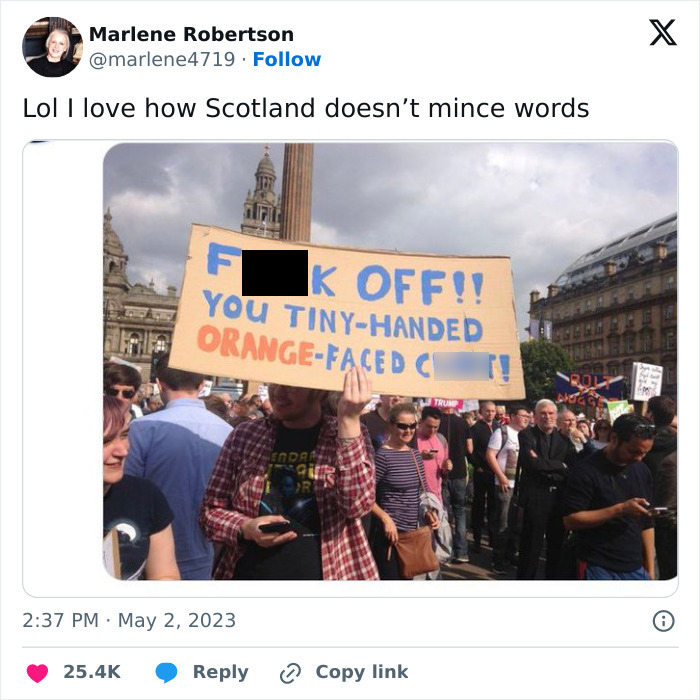 Crowd holding a bold sign, showcasing unique Scottish humor at a public protest.