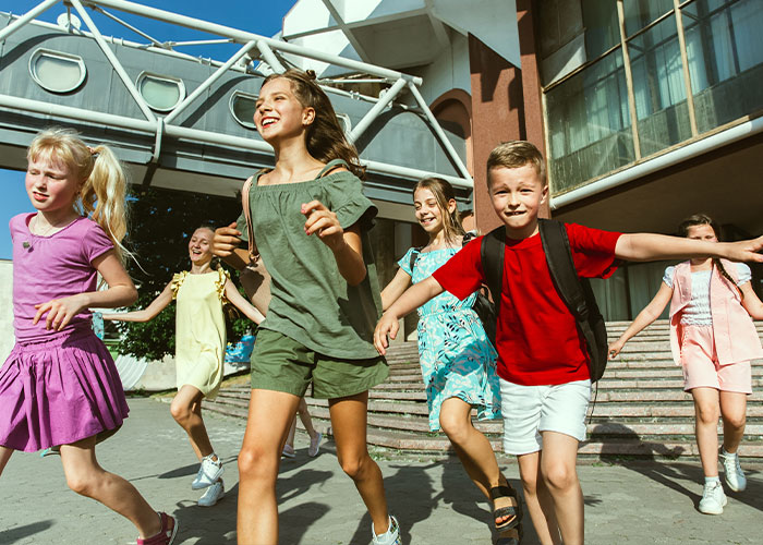Children happily running outside a building, capturing a joyful moment.