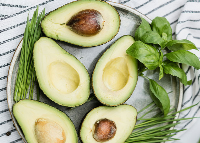 Avocado halves on a plate with herbs, once considered exotic foods.