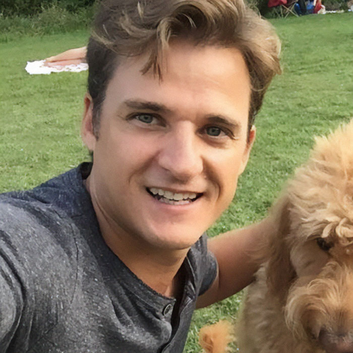 A man smiling in a park setting with a dog, related to a top doctor news story. A man smiling in a park setting with a dog, related to a top doctor news story.