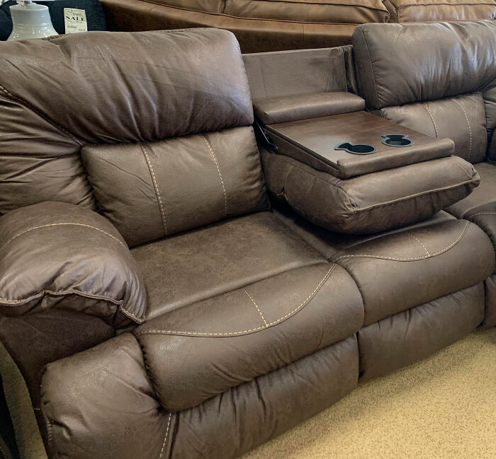 Brown leather reclining sofa with built-in cup holders, illustrating poorly-aging interior design trends in living rooms.
