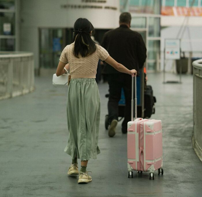 Woman with pink suitcase walking away, symbolizing reasons for friendships ending.