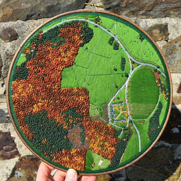 Landscape embroidery art showcasing intricate green fields and roads.