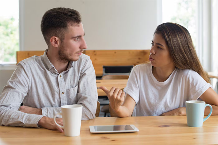 Couple discussing career promotion at a table with coffee and a tablet.