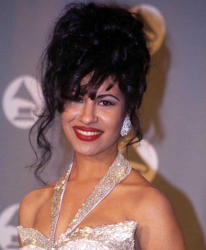 Smiling woman in a glamorous dress at a Hollywood event, symbolizing celebrity assassinations.