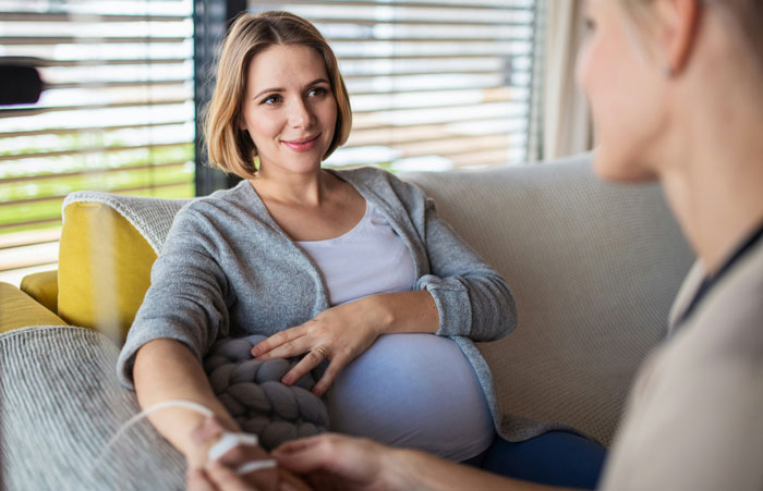 Pregnant woman on sofa receiving support, in context of cruise plans during possible early birth.