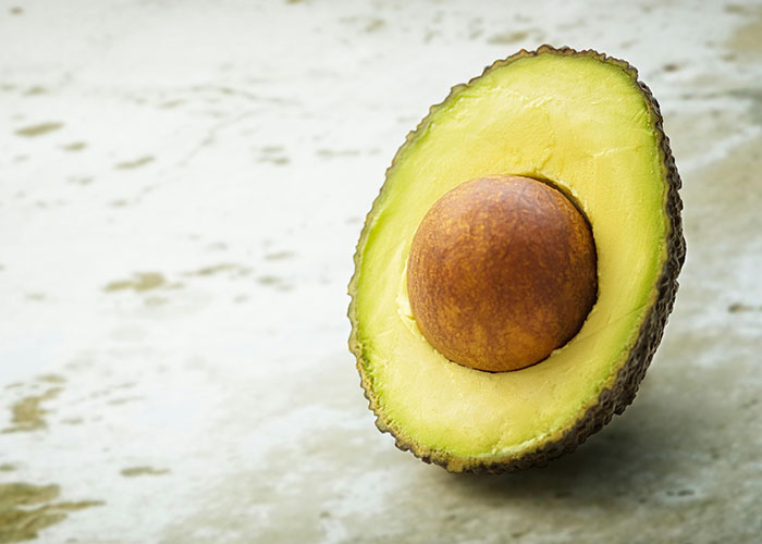 Half an avocado on a textured surface, illustrating natural beauty tips.