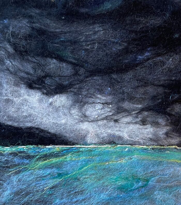 Fiber artwork depicting a dramatic seascape with dark sky and vibrant blue-green water.
