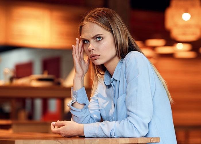 Woman in a blue shirt looking concerned, symbolizing parenting mistakes being repeated with kids.