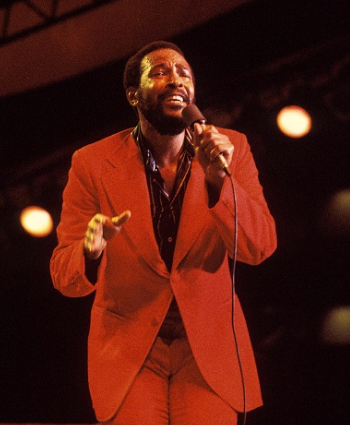 A singer in a red suit performs on stage, spotlighted; notorious celebrity assassinations in focus.