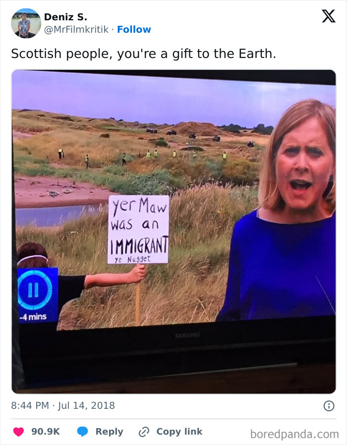 TV broadcast captures Scottish humor with a sign reading "yer maw was an immigrant" held up behind a news reporter.