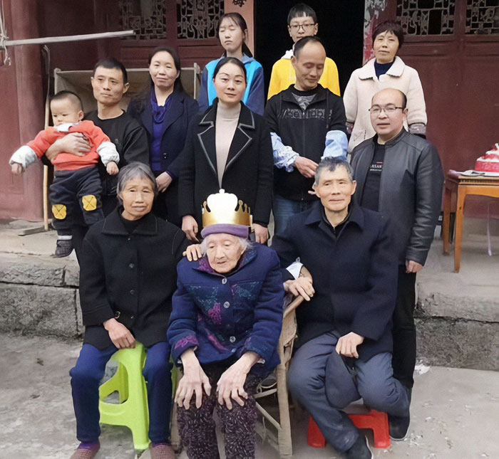Elderly Chinese woman with family gathers around for a group photo.