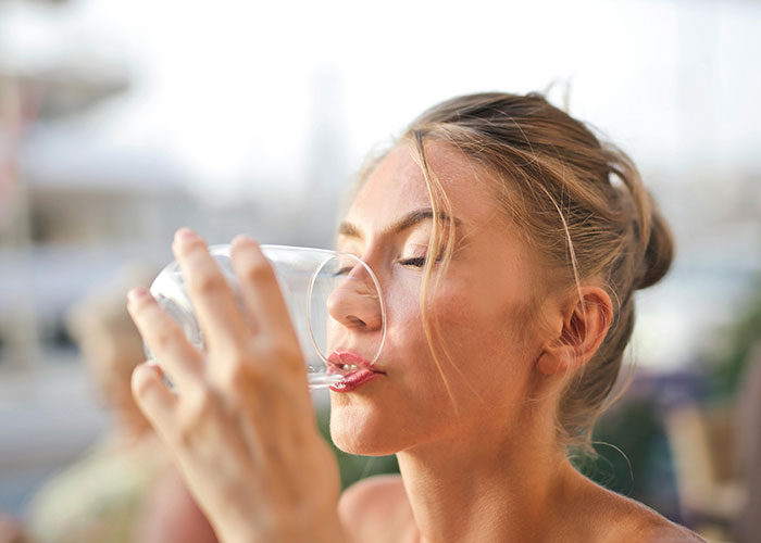 Woman drinking water to enhance beauty with a healthy lifestyle.