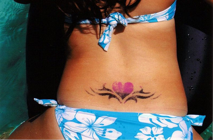 Heart tattoo on lower back, someone wearing a blue floral bikini.