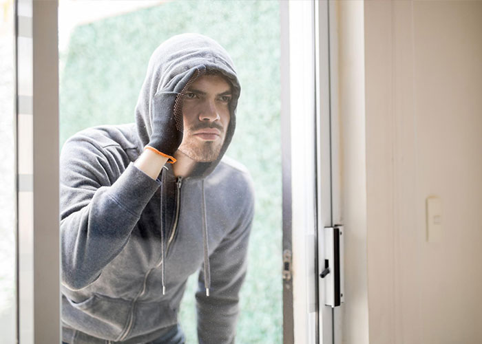 Man in a hoodie peering through a window, evoking memorable dad stories.