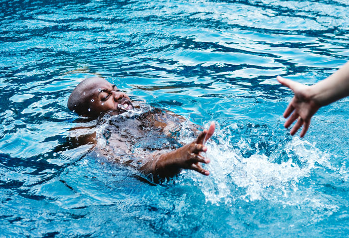 A person in water reaching for a helping hand, highlighting life-saving assistance.