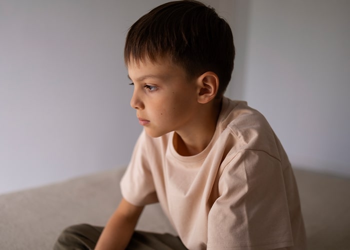 Child sitting, looking thoughtful, as an example of parenting mistakes and reflection.